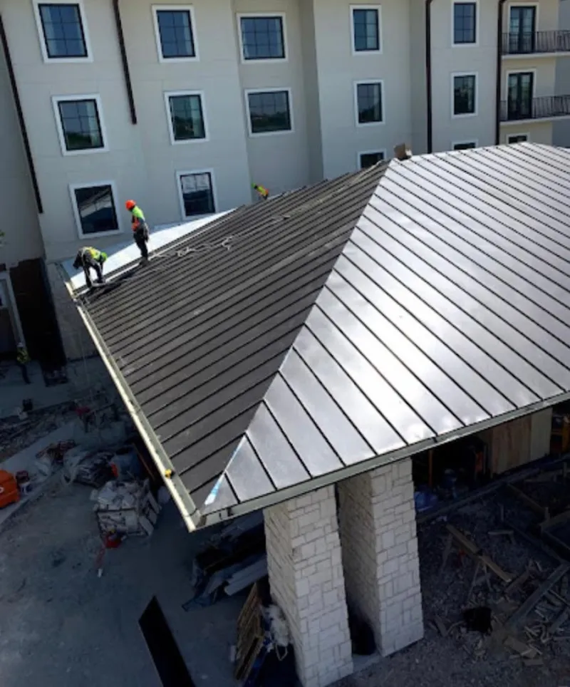 Crew installing standing seam metal roof panels on a commercial project in Warrington